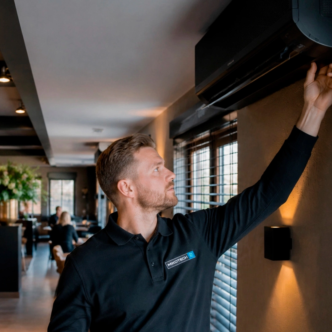 Mikotech monteur controleert een binnenunit in een stijlvolle horecaruimte