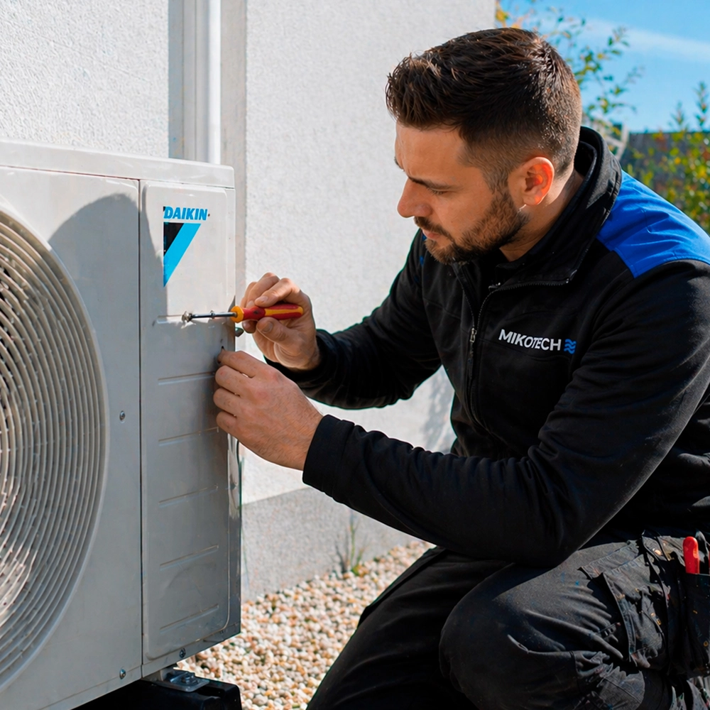 Monteur van Mikotech voert airco reparatie uit aan buitenunit van airconditioning